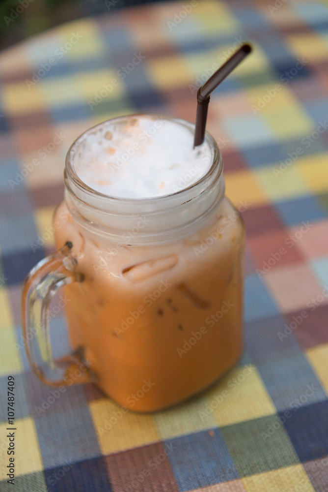 Ice milk tea with straw in cube glass with handle in selective focus Ice milk tea with straw in cube glass with handle in selective focus