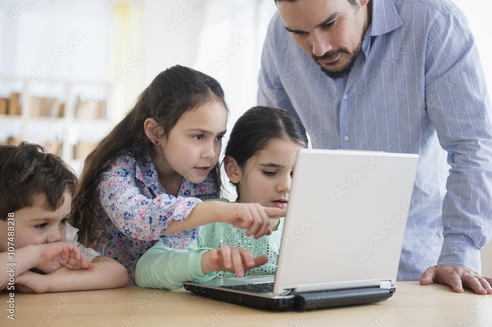 Caucasian father and children using laptop Caucasian father and children using laptop