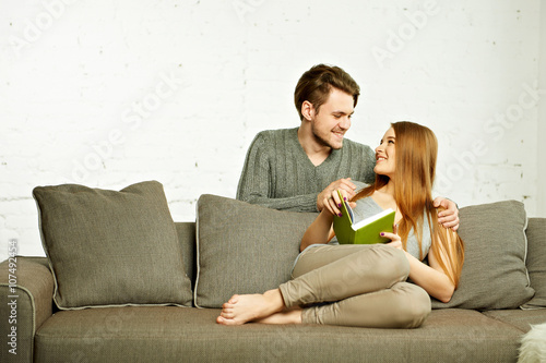 Smiling Romantic Couple With Book Talking on Couch