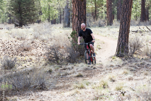 Bald man riding a mountain bike on a dirt trail in the forest