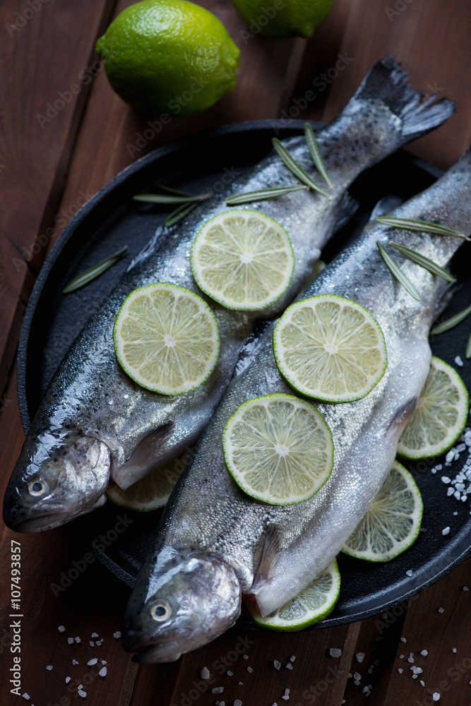 Closeup of raw rainbow trout with lime and sea salt, studio shot