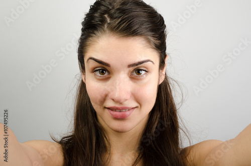 Happy cute woman making selfie over gray background. Looking at camera