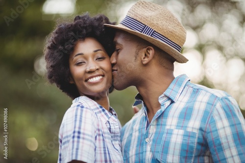 Vászonkép Smiling man kissing her girlfriends cheek