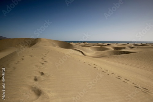 Sand dunes with steps in the sand to infinity. Beautiful nature beach on the island. Wide shot. Desert expedition. Spain - Gran Canaria - Maspalomas