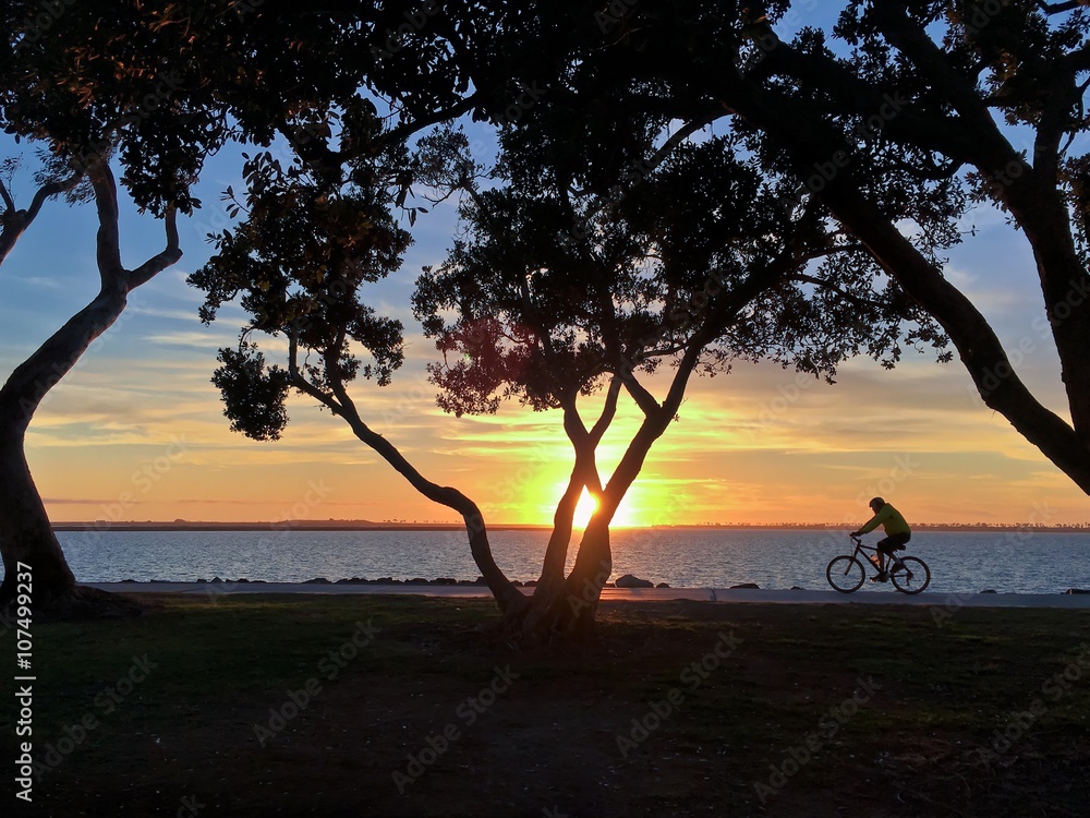 Sunset Silhouette of a man riding a bicyle along waterfront