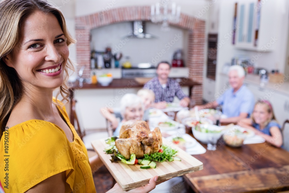 Portrait of happy woman holding a tray of roasted turkey