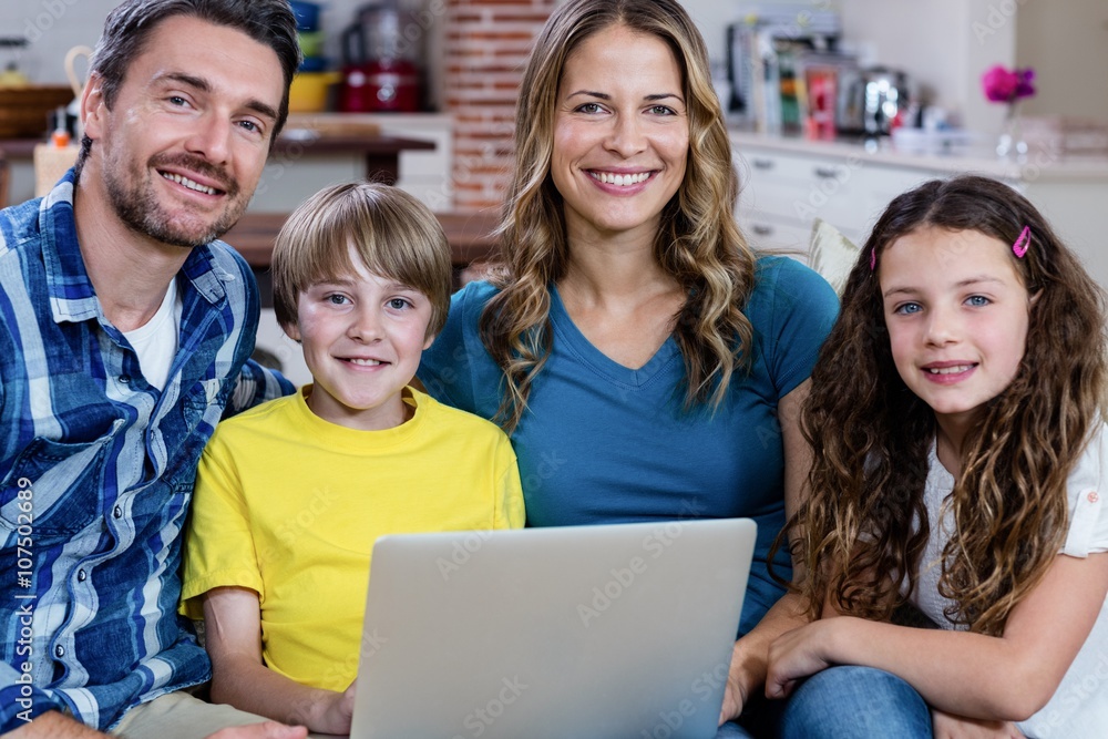 Portrait of parents and kids sitting on sofa and using a laptop Portrait of parents and kids sitting on sofa and using a laptop