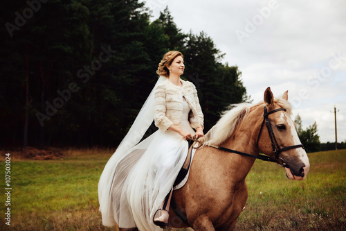 Beauty bride in white dress with horse in the autumn forest