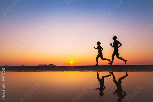 workout  silhouettes of two runners on the beach at sunset  sport and healthy lifestyle background