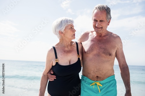 Happy senior couple embracing while walking on beach
