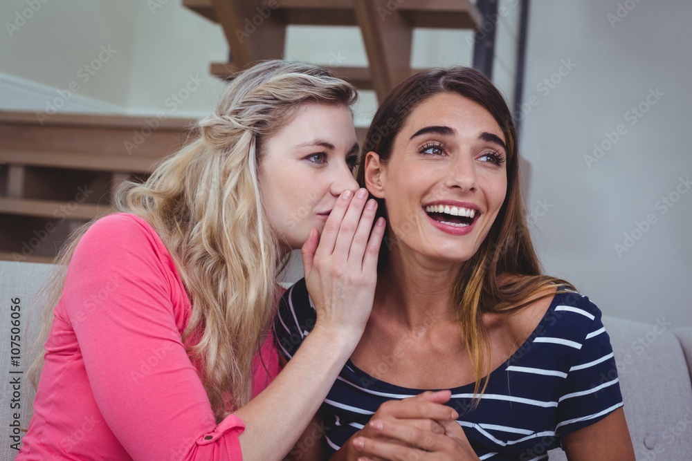Young woman whispering a secret to her friend Young woman whispering a secret to her friend