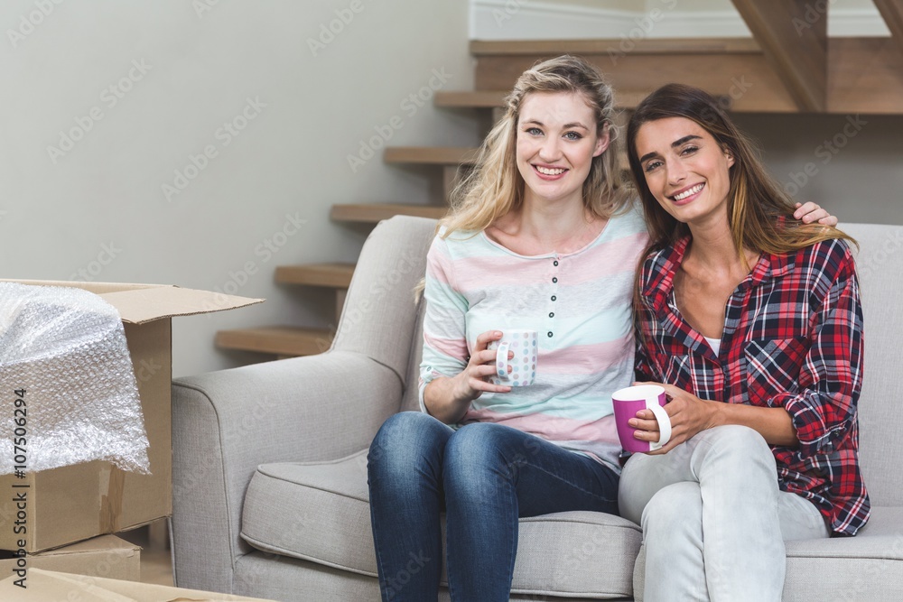 Two beautiful women sitting side by side with a mug of coffee Two beautiful women sitting side by side with a mug of coffee