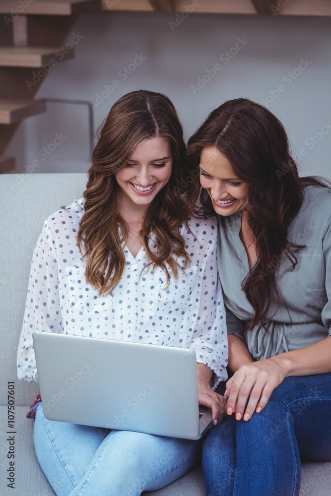 Two beautiful women using a laptop in living room Two beautiful women using a laptop in living room