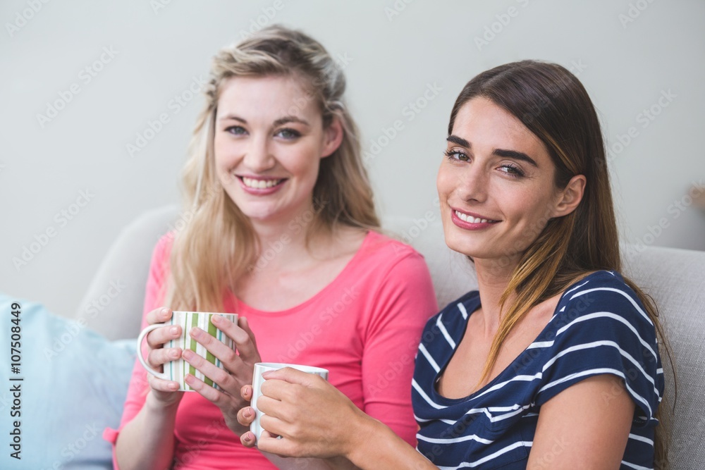 Two beautiful women sitting side by side with a mug of coffee Two beautiful women sitting side by side with a mug of coffee