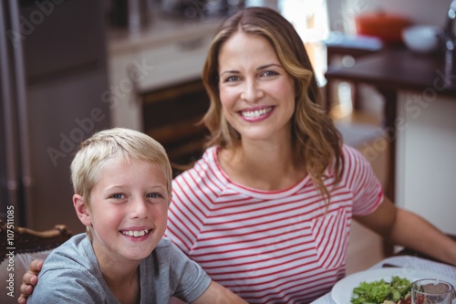Smiling mother and son sitting at dining table