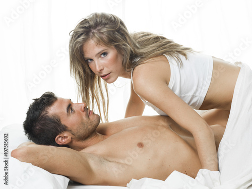 attractive couple in love under white bed sheets