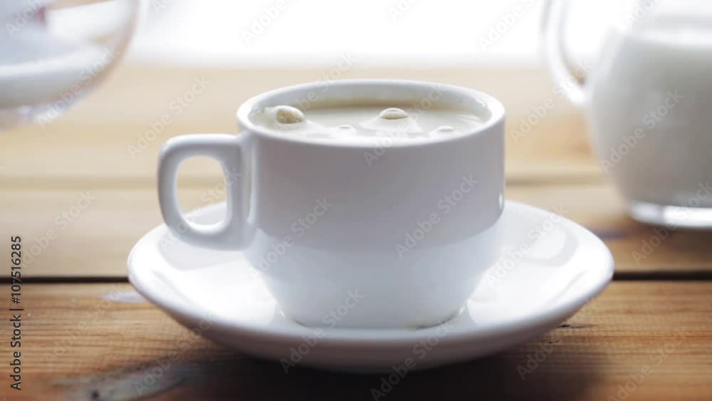 hand pouring sugar by teaspoon into coffee cup hand pouring sugar by teaspoon into coffee cup