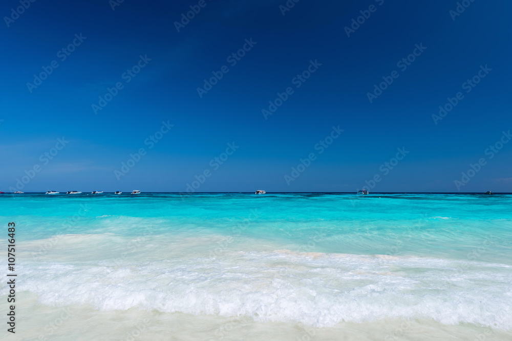 Water clear at the sandy beach with blue sky