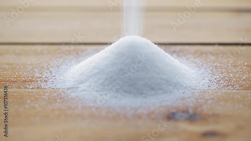 white sugar pouring into heap on wooden table