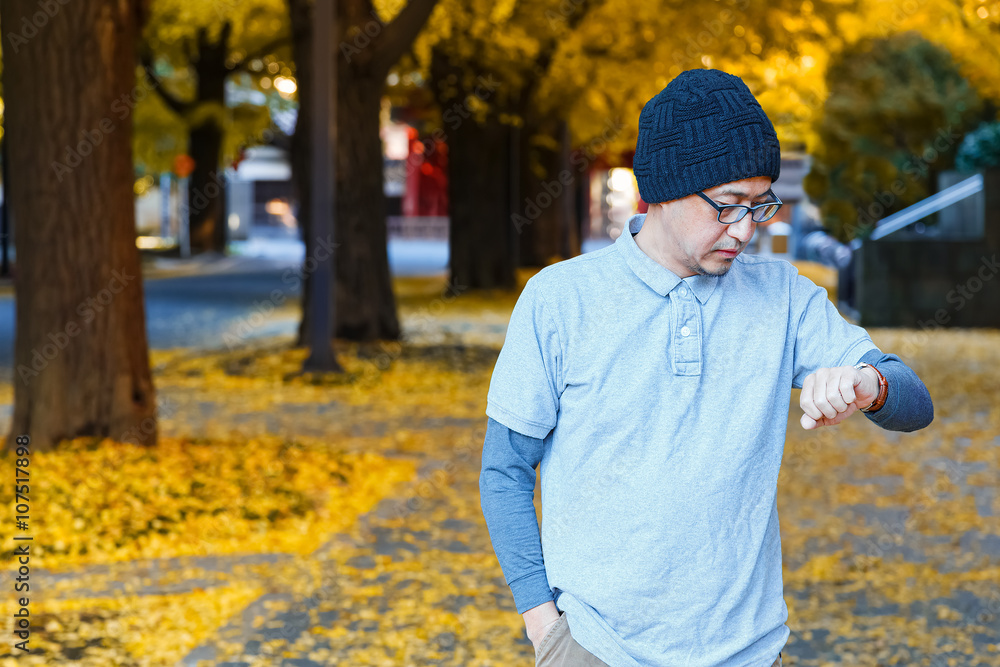 An asian man in a polo t-shirt walks on a street An asian man in a polo t-shirt walks on a street