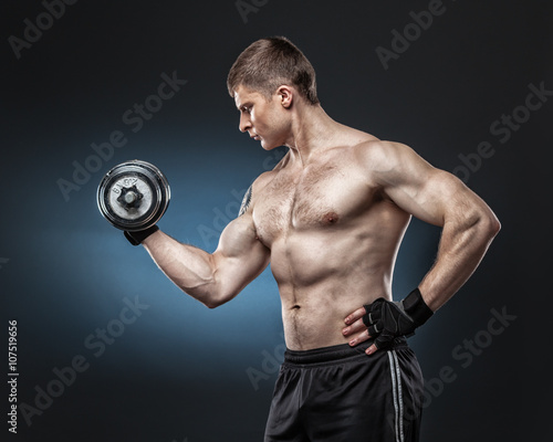 Muscular yong man exercising with dumbbell