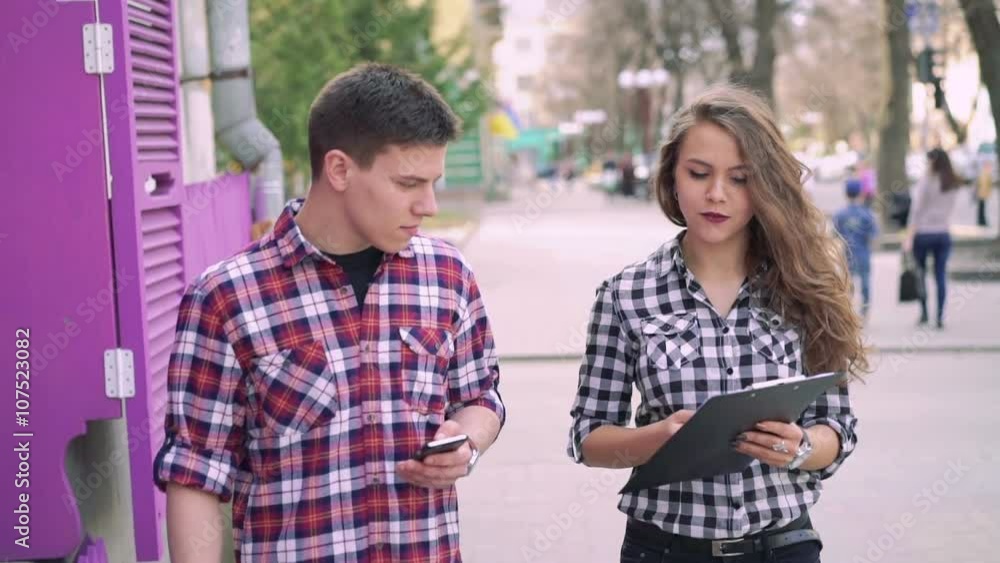 Girl and boy walking, speaking, using phone and notebook. Slowly Girl and boy walking, speaking, using phone and notebook. Slowly