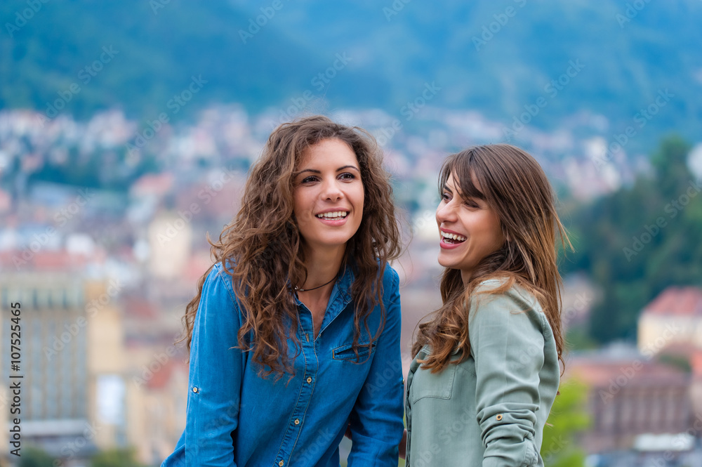Fototapeta premium Two women friends laughing and hugging outdoors having a good time.