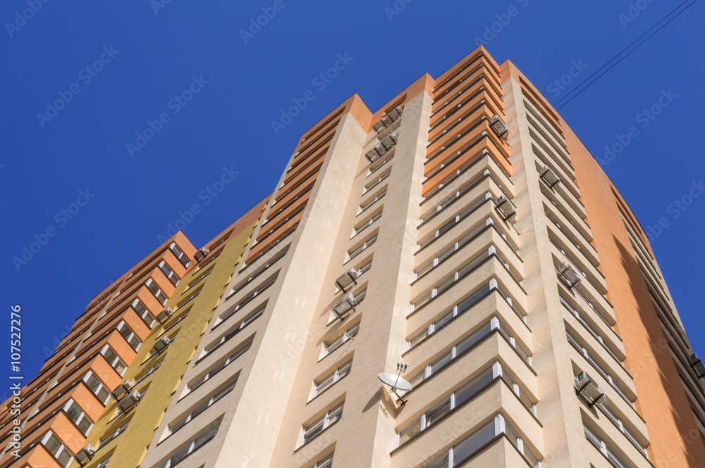 Big colorful apartment building with conditioners against blue sky in residential settlement