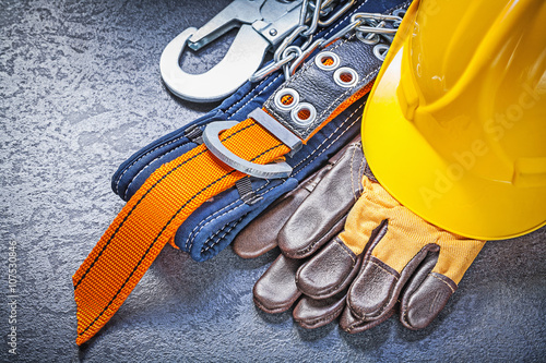 Construction safety harness protective gloves hard hat on black 