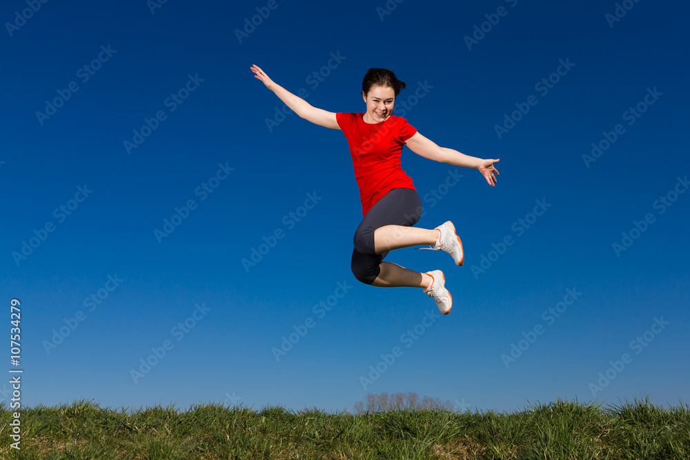 Teenage girl jumping outdoor against blue sky Teenage girl jumping outdoor against blue sky