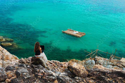 Obraz na płótnie Woman freelancer feeling happy with laptop. Amazing seaview with blue lagoon with rocks. w salonie
