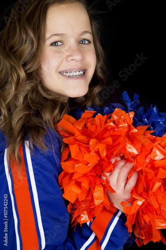 Portrait of teen cheerleader holding pom poms smiling with brace photo