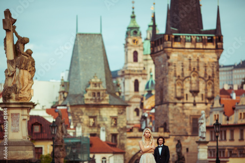 Beautiful blonde bride & handsome groom posing on Prague bridge,