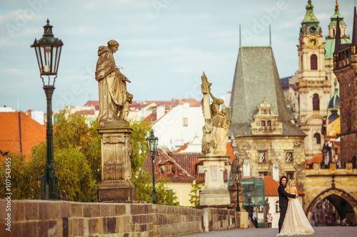 Romantic newlywed couple on honeymoon, hugging on bridge in Prag
