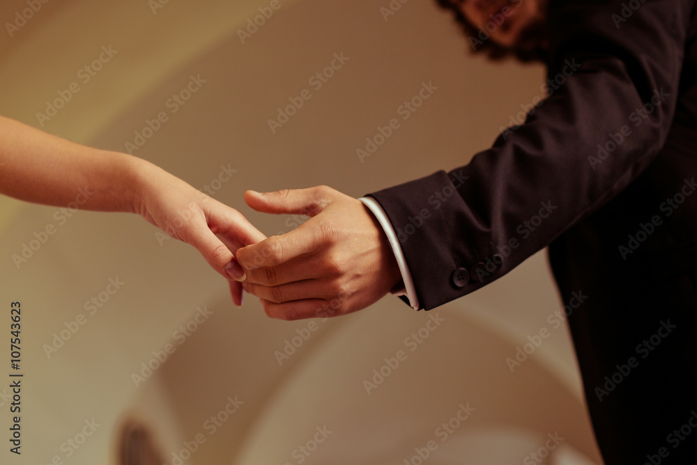Romantic emotional newlyweds holding hands under building archwa