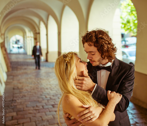 Romantic emotional newlyweds hugging under building archway clos