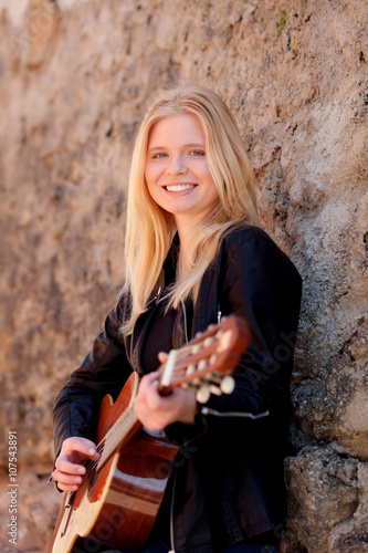 Cool blonde girl playing guitar outdoor