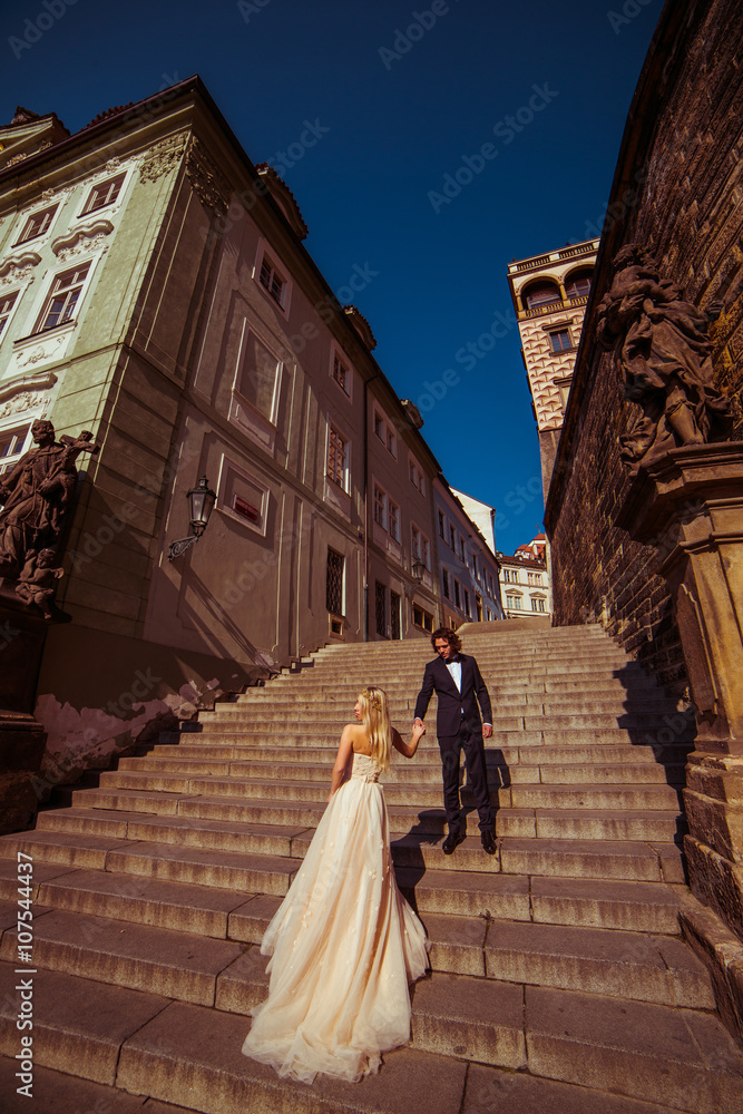 Sensual couple of newlyweds holding hands on old medieval stairs