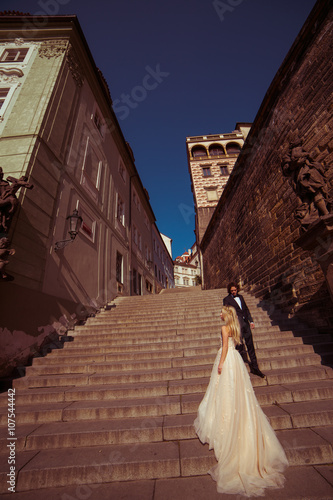 Sensual couple of newlyweds holding hands on old medieval stairs © pyrozenko13