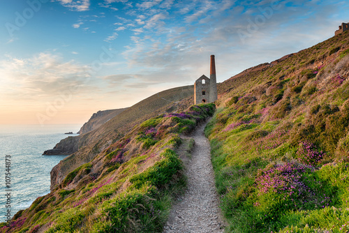 Hazy summer evening on the South West Coast Path as it approaches the ruins of the Wheal Coates mining engine house near St Agnes in Cornwall photo