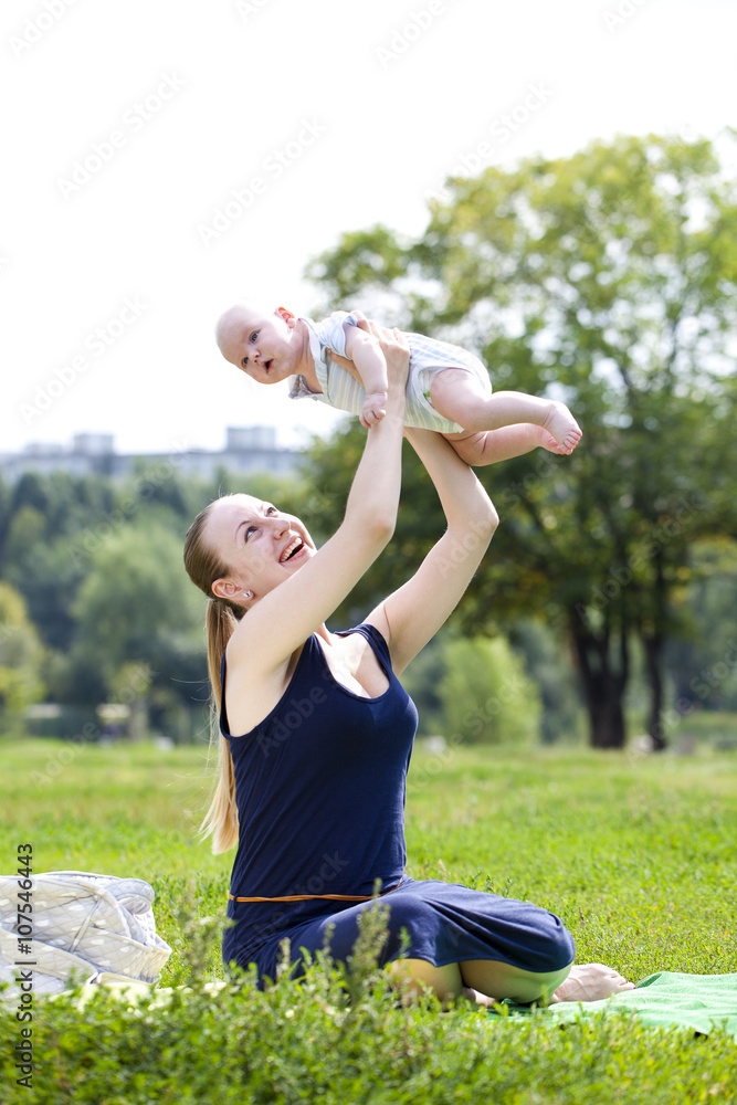 Caring mother is holding the baby, against summer park Caring mother is holding the baby, against summer park