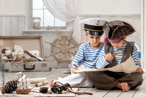Fototapeta Chłopcy przebrani za piratów i czytają mapę podróży