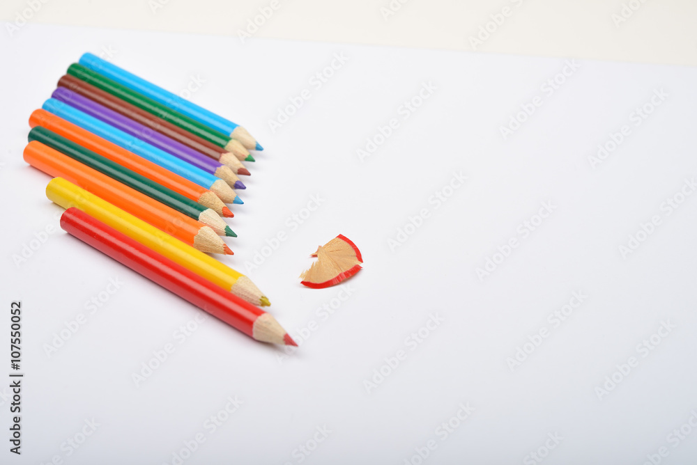 Fototapeta premium Close up of arranged colored pencils with pencil shavings on whi