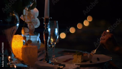Close up of a men hands eating a dessert on the date by candlelight at night