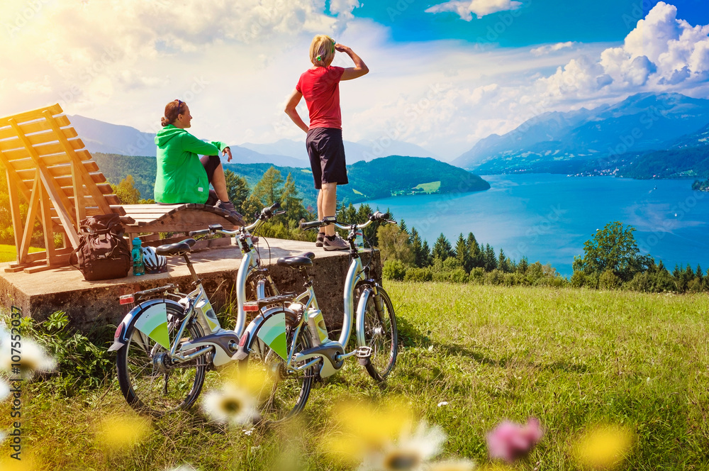 Obraz premium Frauen mit e-bike genießen Ausblick auf See-sportive holidays 0