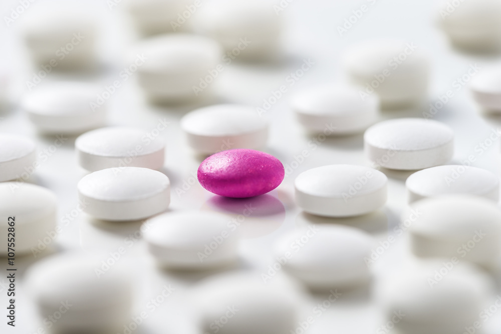 White pills  with a pink one  on white backgroung background.