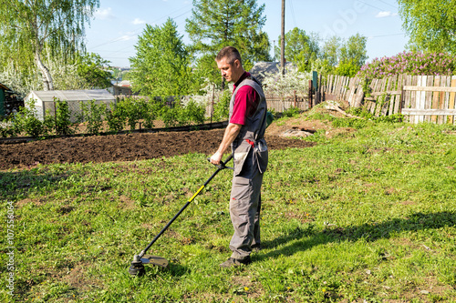 Man mowing grass with a trimmer