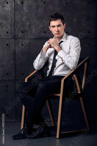 Portrait of strict young businessman in black studio