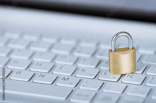 Small padlock sitting on white computer keyboard, online security concept