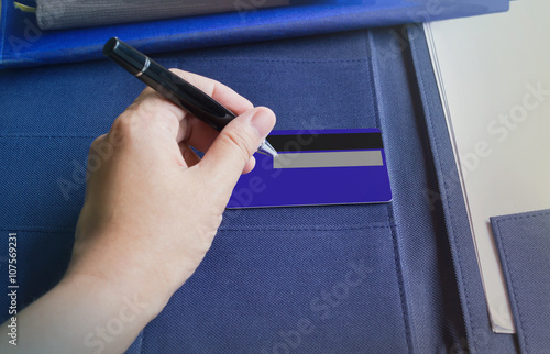 Hand with pen sign or writing down at the back of credit card photo